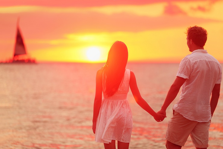 Honeymoon couple romantic in love holding hands at beach sunset.